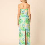 back of woman in printed midi dress on tan background 