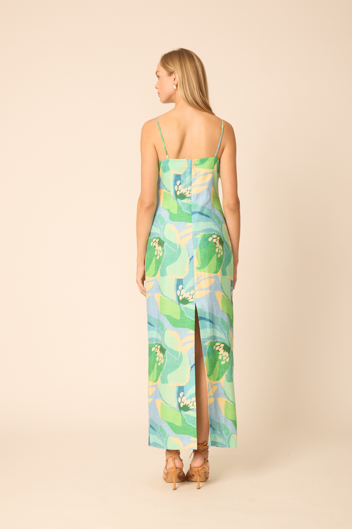 back of woman in printed midi dress on tan background 