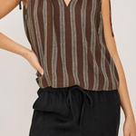 Person wearing a brown striped sleeveless top and black pants on a plain background