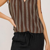 Person wearing a brown striped sleeveless top and black pants on a plain background