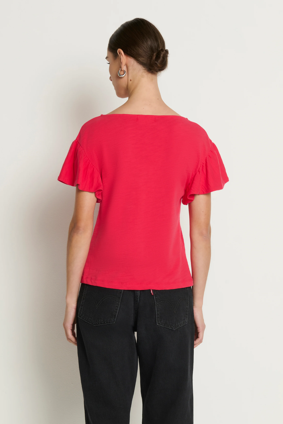 Person wearing a red top and black pants against a white background