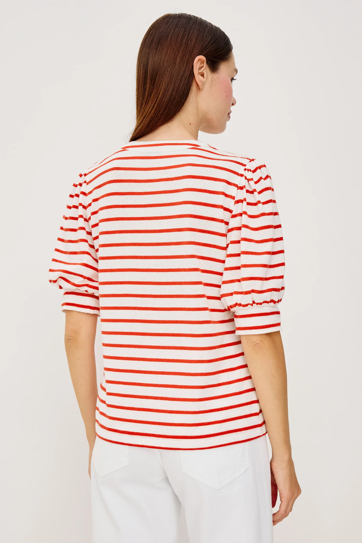 back of woman in red and white stripe top on white background 