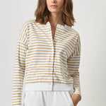 Woman wearing a striped shirt and white pants against a plain background