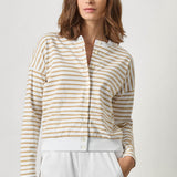 Woman wearing a striped shirt and white pants against a plain background