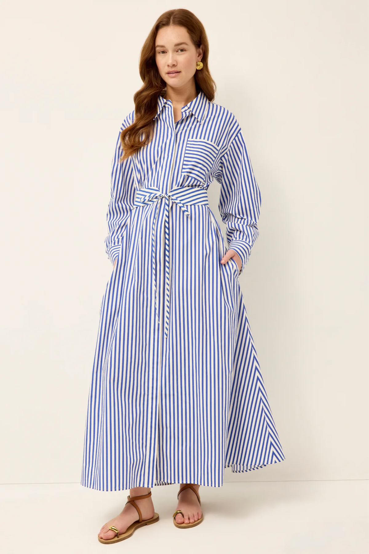 Woman wearing a blue and white striped dress against a plain background