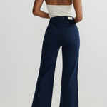 Person wearing a white top and navy high-waisted pants on a plain background