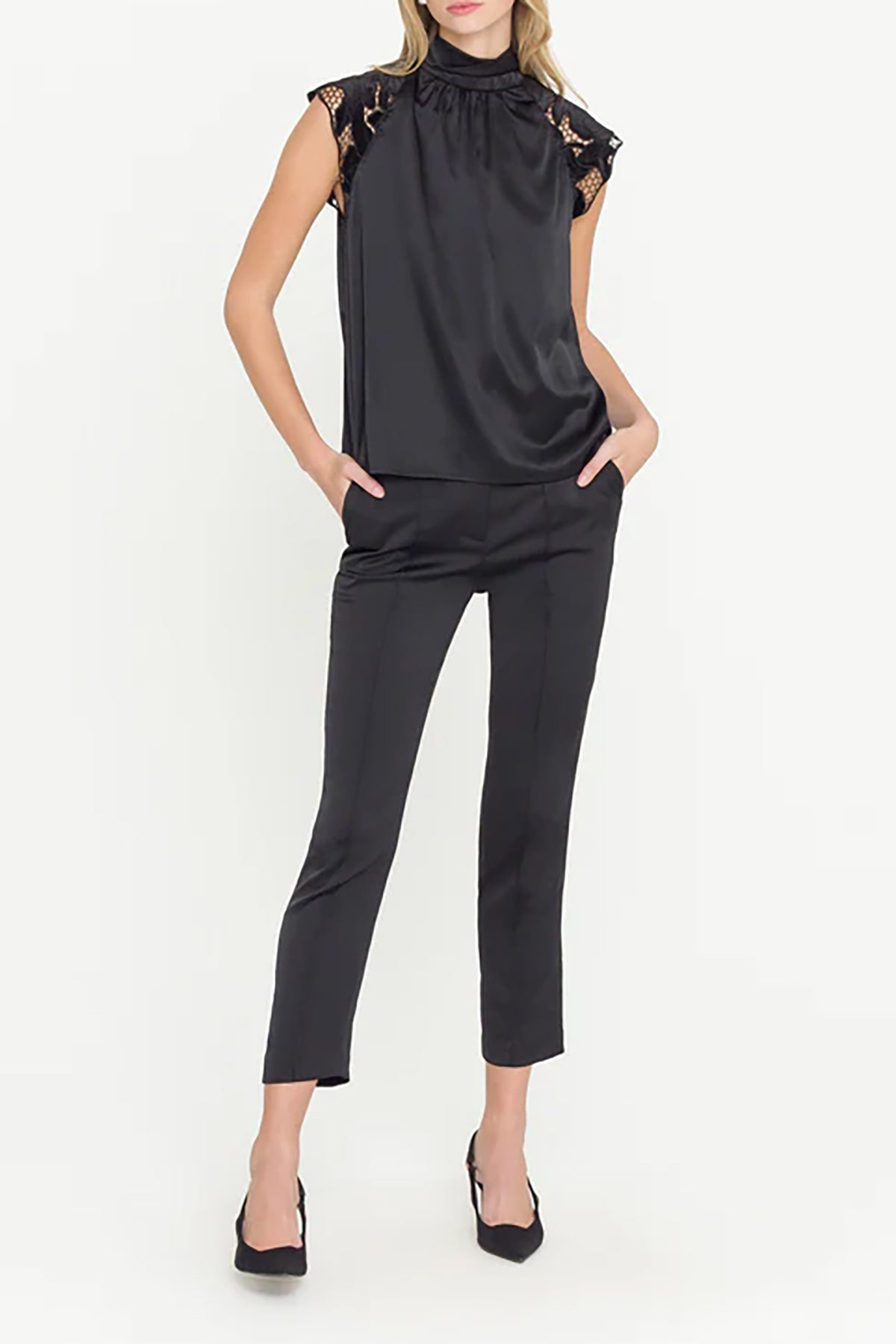 Woman wearing a black sleeveless top and pants on a white background