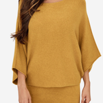 A woman wearing a mustard yellow knit two-piece set consisting of a wide-sleeve top and matching pants, shown against a plain light gray background.