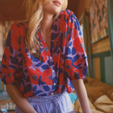 Woman in a colorful shirt holding a book in a room with a couch and decorative wall.