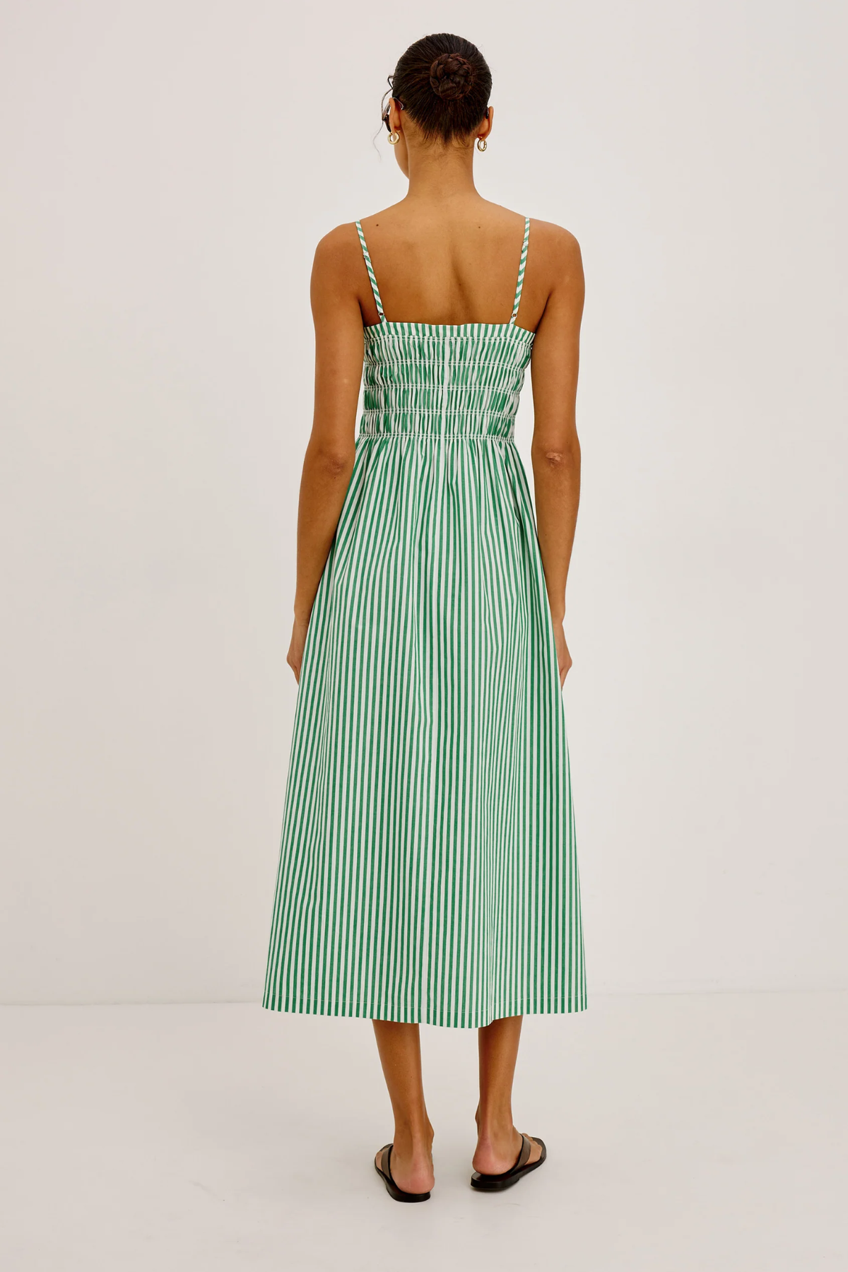 Woman wearing a green and white striped dress on a plain background