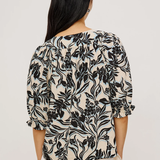 Woman wearing a black floral patterned top against a white background