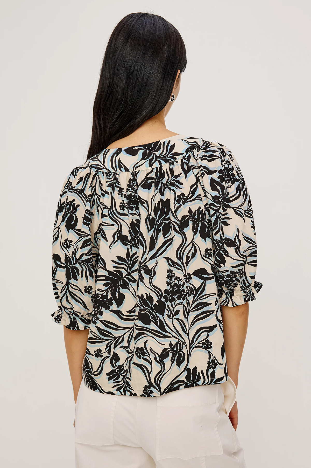 Woman wearing a black floral patterned top against a white background