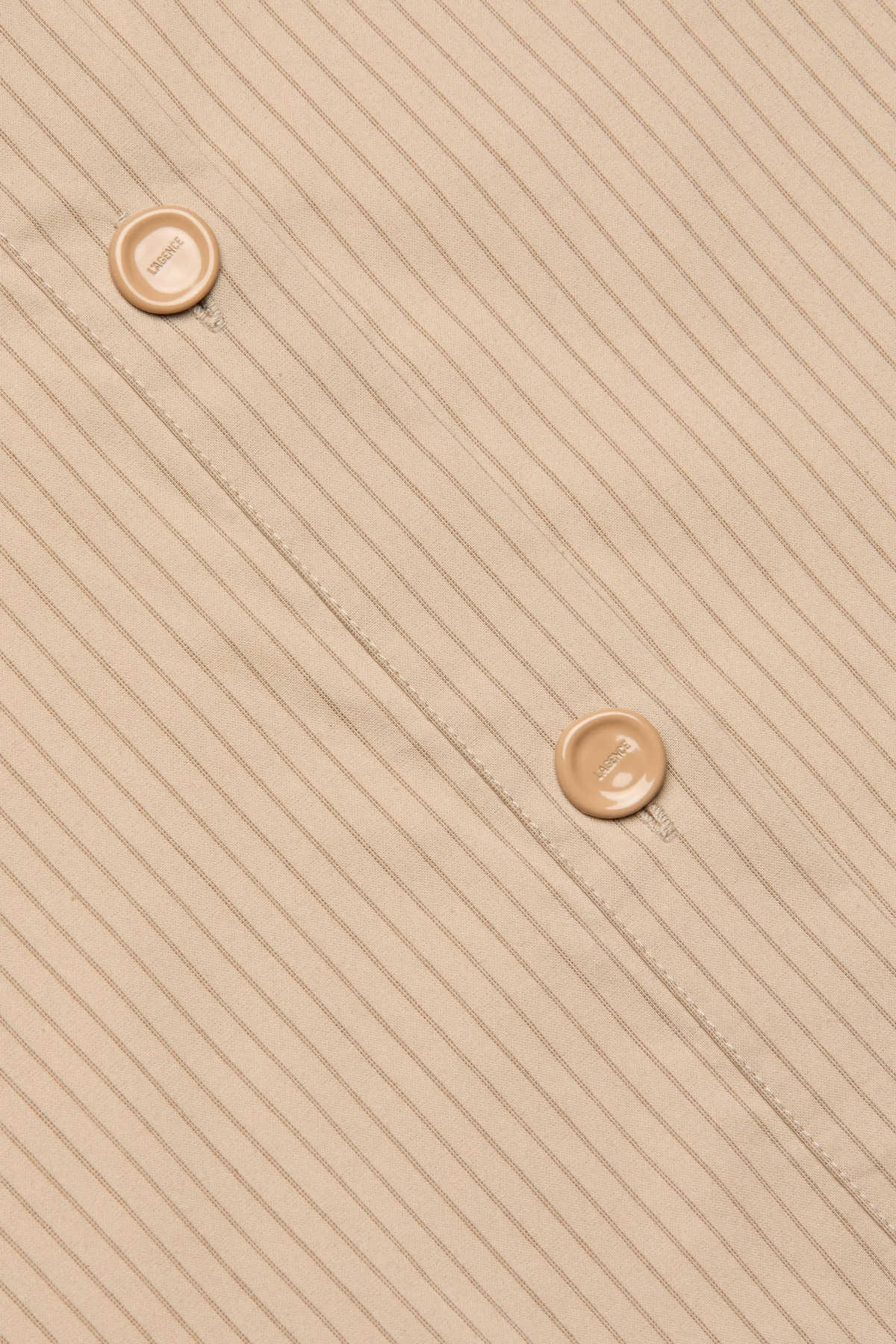 Beige fabric with a subtle pattern and two buttons on a diagonal line.