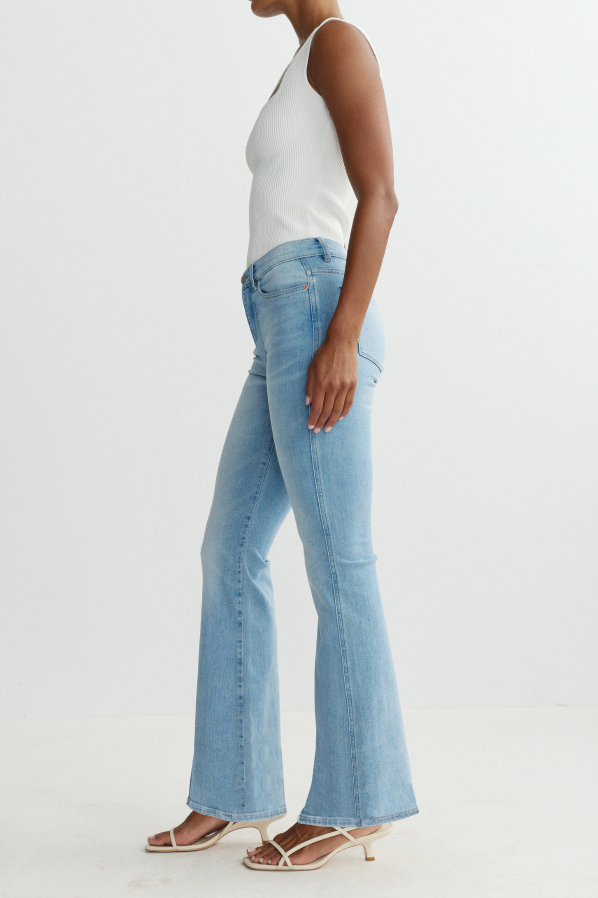 Person wearing light blue jeans and a white top on a plain background