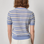 Person wearing a blue and white patterned short-sleeve shirt on a plain background