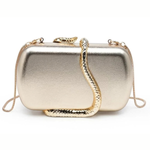 A metallic gold clutch bag with a textured snake-shaped strap draped over the front, set against a plain white background.