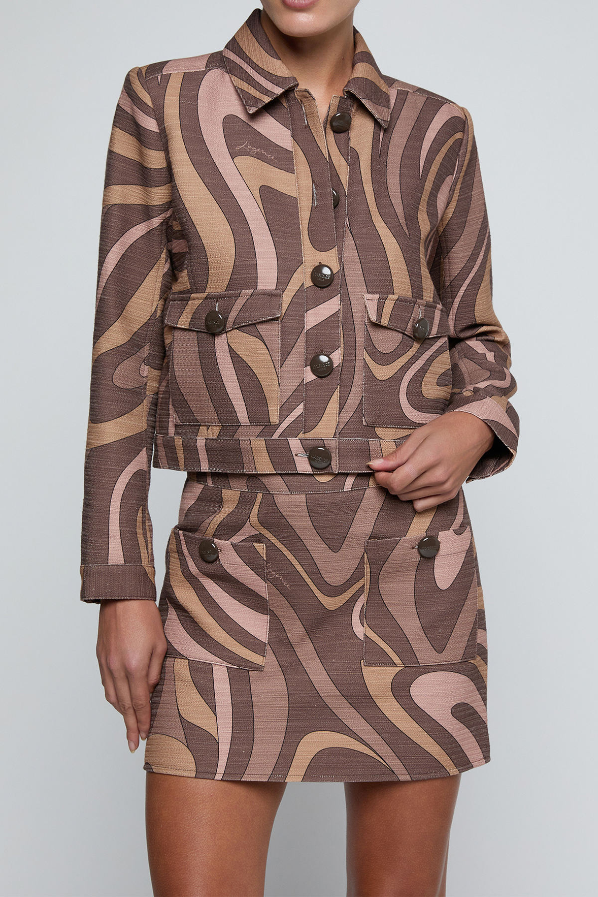 Model wearing a cropped printed jacket featuring a textured neutral-toned pattern with a modern tailored silhouette.