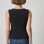 A woman viewed from the back wearing a sleeveless ribbed black top and blue jeans against a light gray studio background.