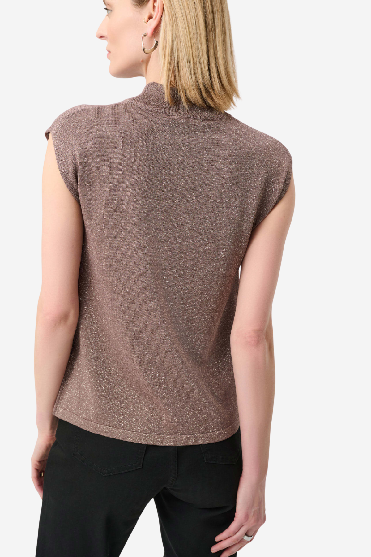 A woman shown from the back wearing a sleeveless mock neck knit top in a dusty mauve-brown color, paired with black trousers, against a light gray studio background.