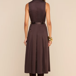 A woman shown from the back wearing a sleeveless dark brown midi dress with a matching belt, paired with dark brown boots, against a solid beige studio background.