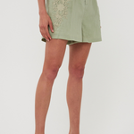 Person wearing a light green skirt with embroidery on a plain background