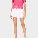 woman in pink lace top and white shorts on white background 