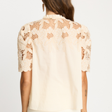 Woman wearing a beige lace blouse on a white background