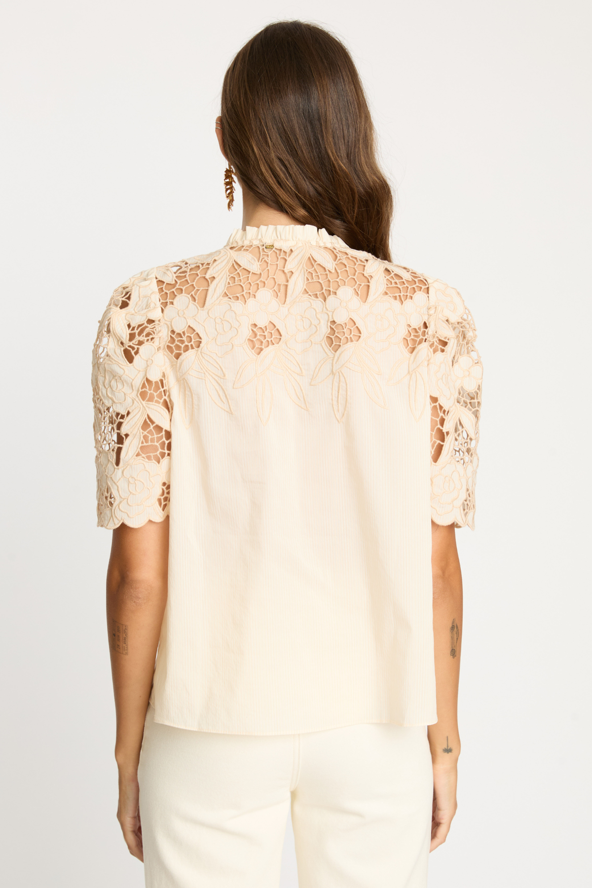 Woman wearing a beige lace blouse on a white background