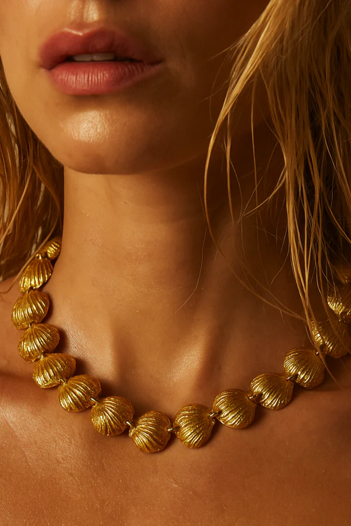 Close-up of a person wearing a gold necklace with a blurred background