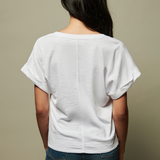 Person wearing a white t-shirt and blue jeans against a beige background