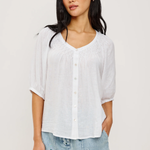 Woman wearing a white blouse and denim shorts on a plain background