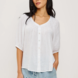 Woman wearing a white blouse and denim shorts on a plain background