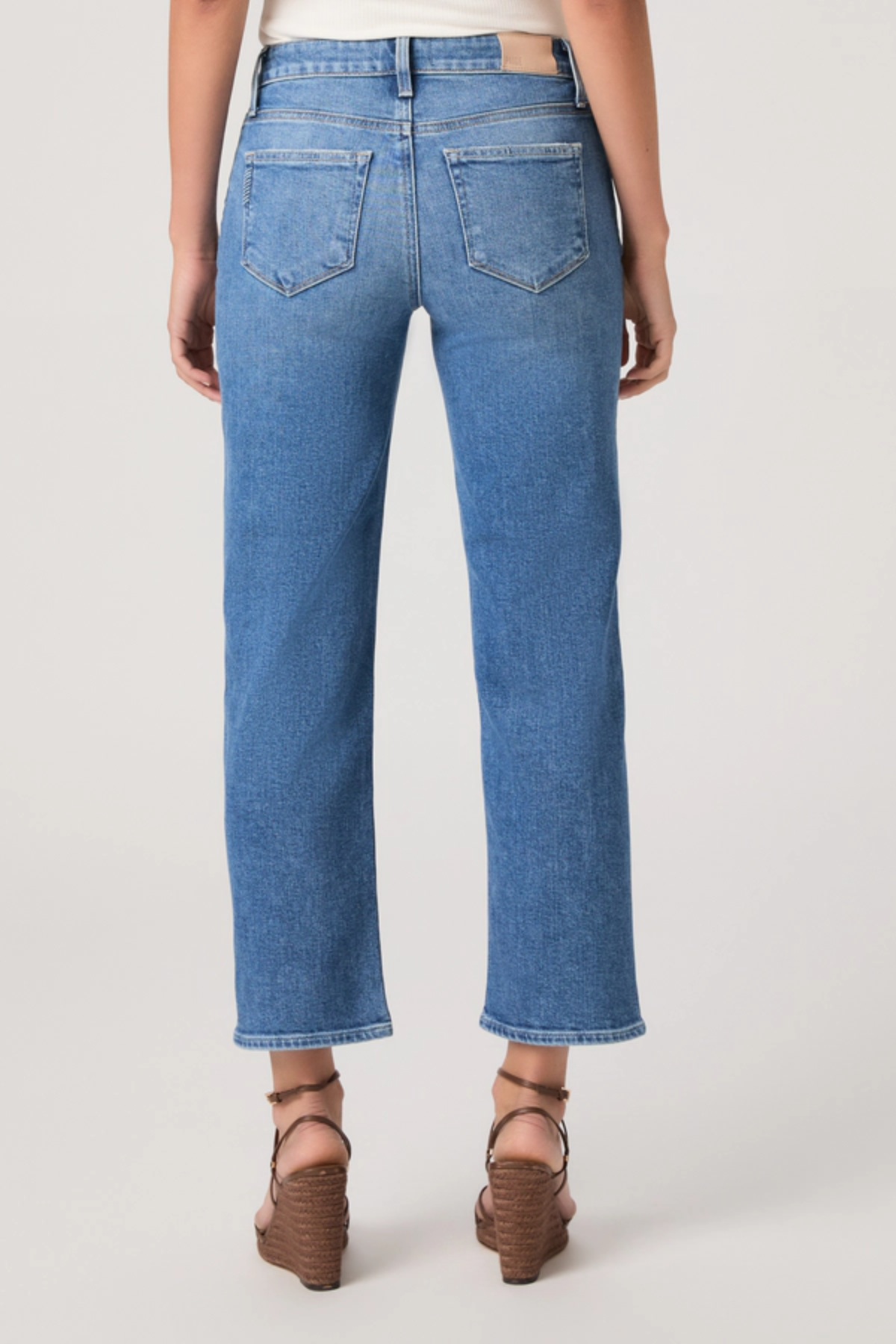 Person wearing blue jeans on a plain background