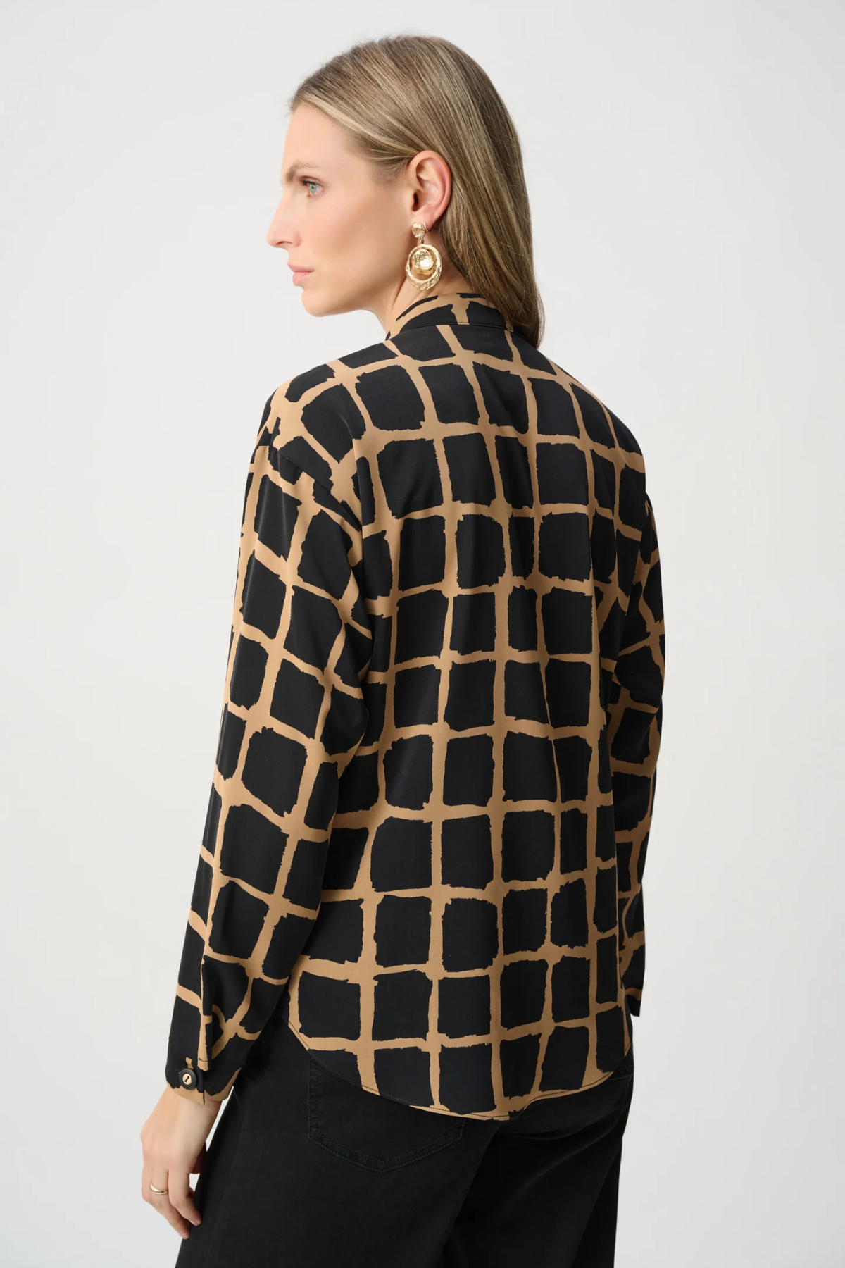 Woman wearing black and gold patterned top against a white background