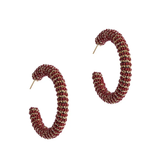 A pair of textured, spiral-shaped hoop earrings in a deep red and gold pattern, displayed on a clean white background.