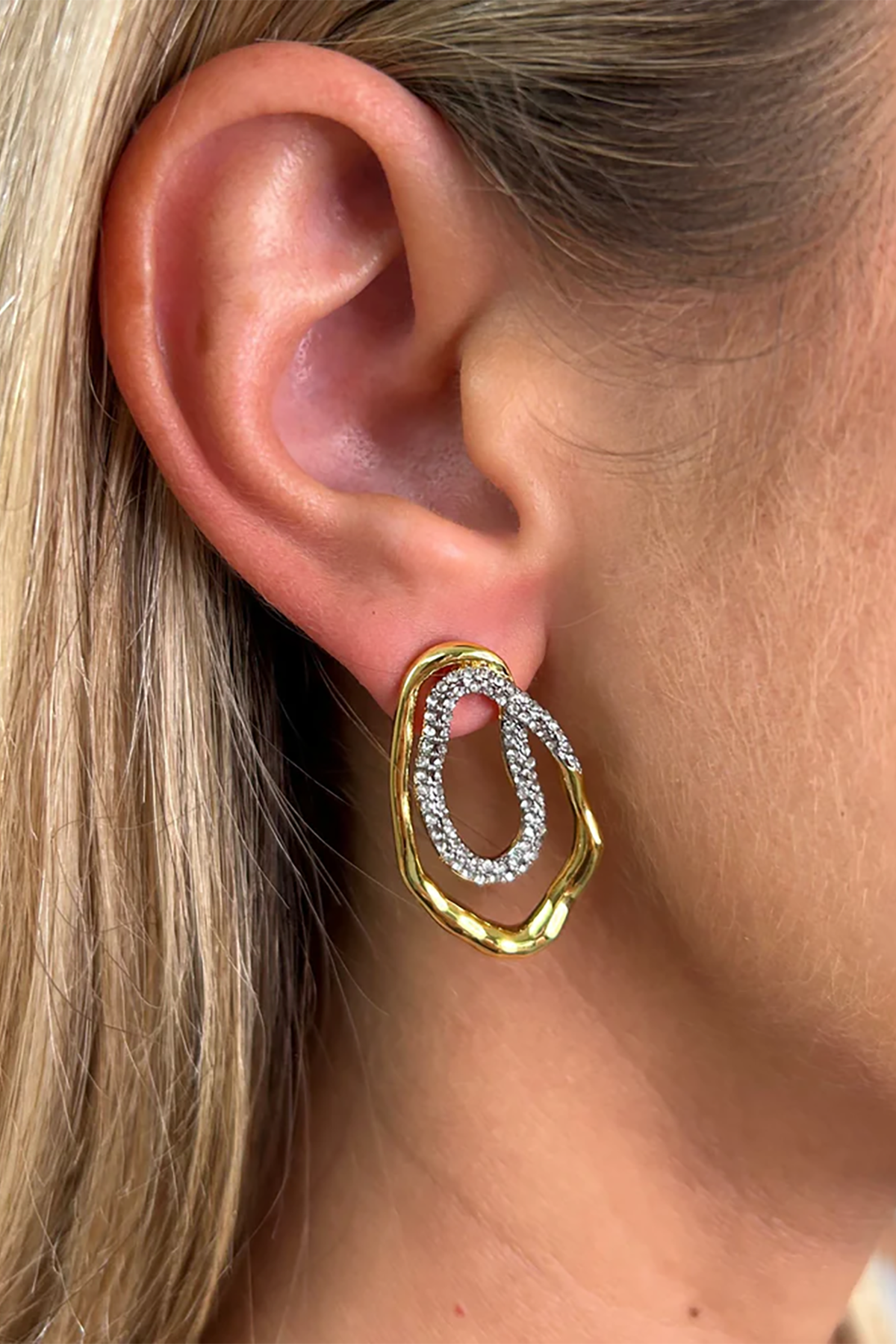 Gold and silver hoop earring worn by a person with blonde hair.