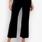 A model wearing black cropped wide-leg trousers with a subtle sheen, paired with a white top and white heeled sandals, set against a plain white studio background.