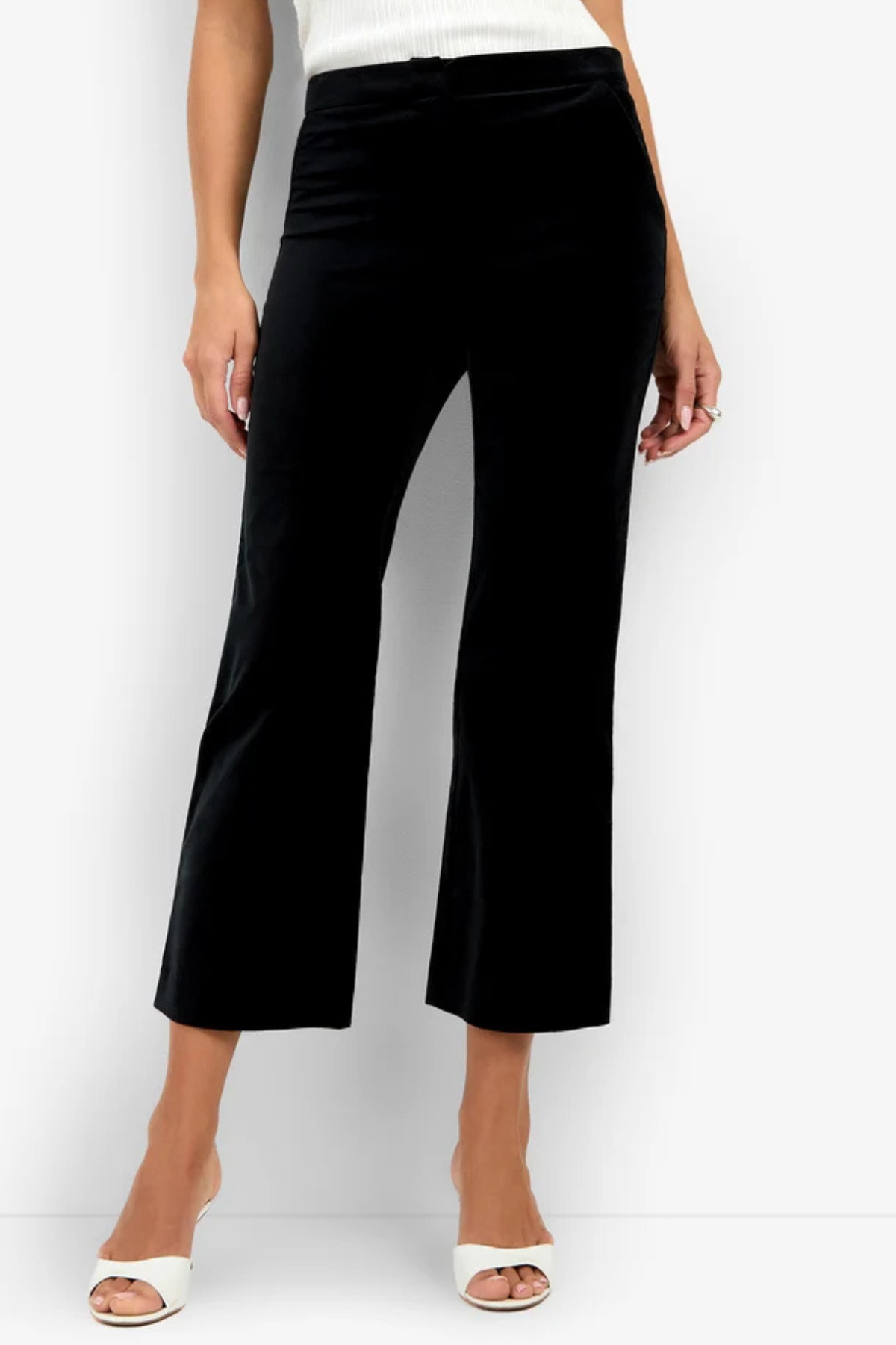 A model wearing black cropped wide-leg trousers with a subtle sheen, paired with a white top and white heeled sandals, set against a plain white studio background.