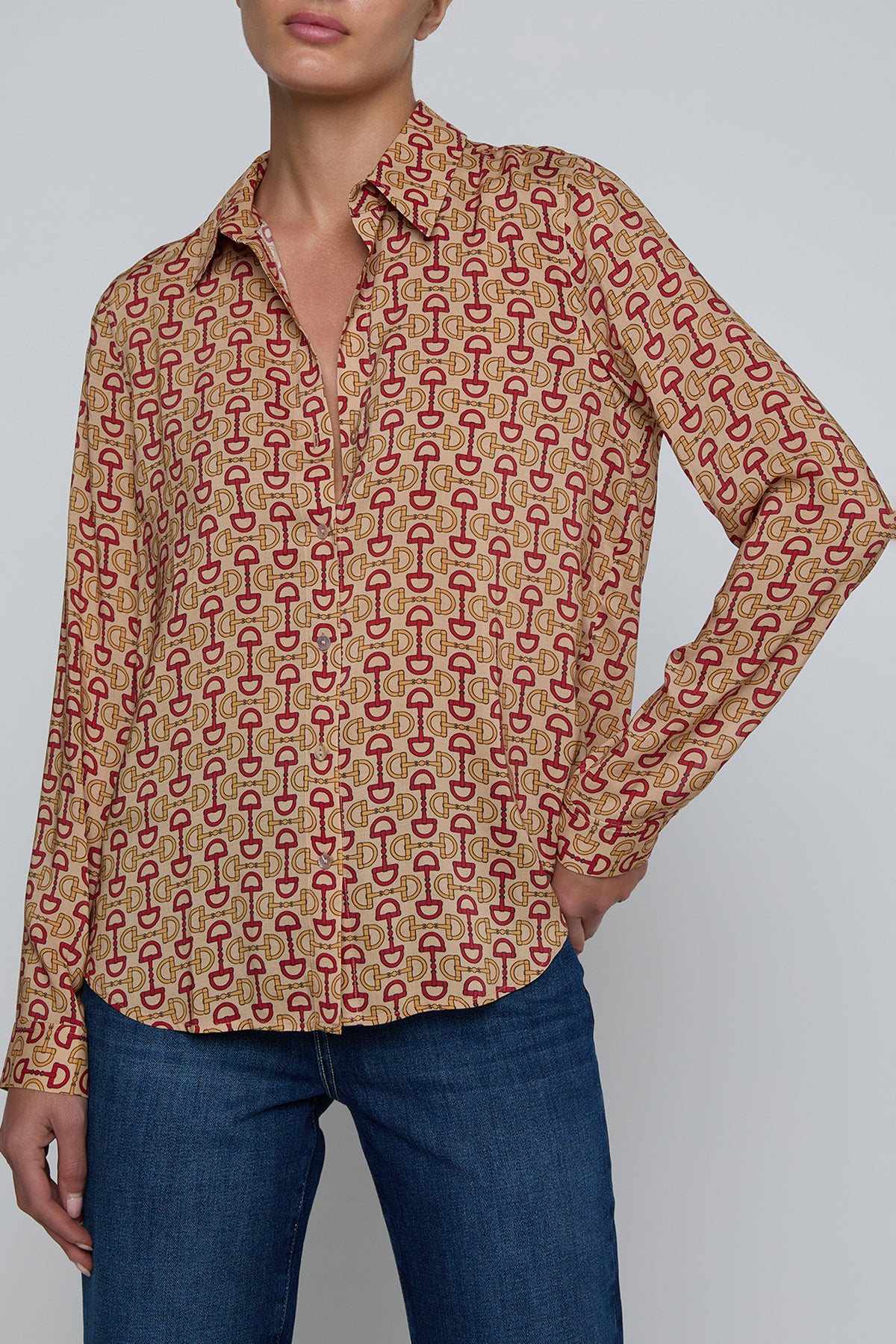 Person wearing a horsebit shirt with long sleeves and blue jeans on a plain background 