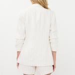 Person wearing a white blazer and shorts set on a white background