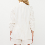 Person wearing a white blazer and shorts set on a white background
