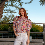 woman in printed blouse outside under a tree 