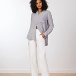 Woman wearing a gray blazer and white pants against a white background