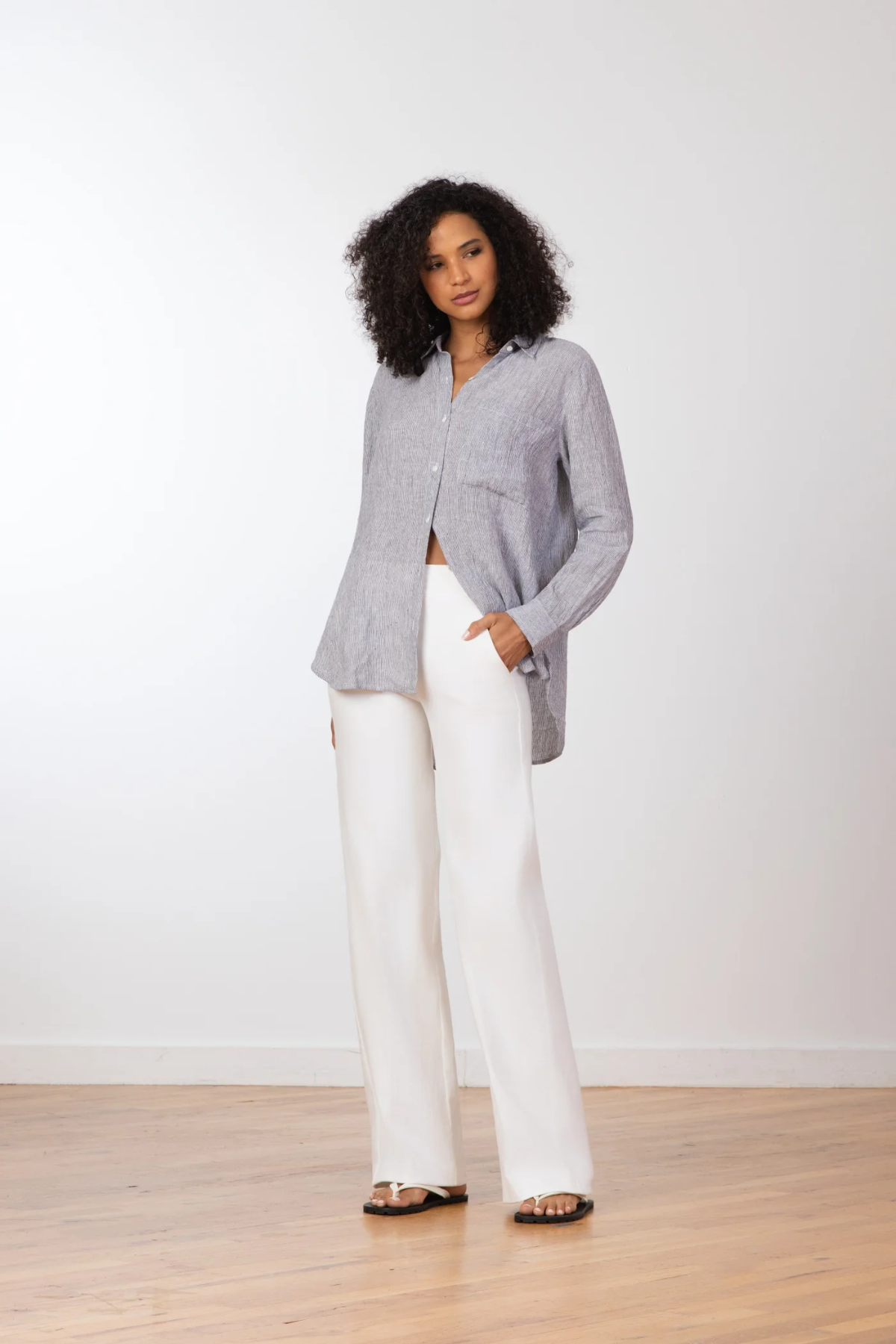 Woman wearing a gray blazer and white pants against a white background