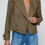 Model wearing a printed trench jacket with jeans on an off white background.