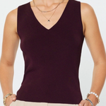 Woman wearing a dark purple sleeveless top and beige pants against a white background
