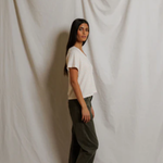 Woman standing against a plain white curtain