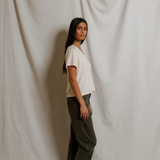 Woman standing against a plain white curtain