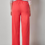 Person wearing a striped shirt and coral pants on a plain background