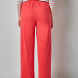 Person wearing a striped shirt and coral pants on a plain background